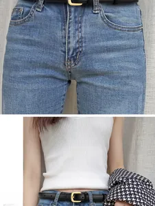 Détail d'une ceinture en cuir noir avec boucle dorée sur un jean bleu et un débardeur