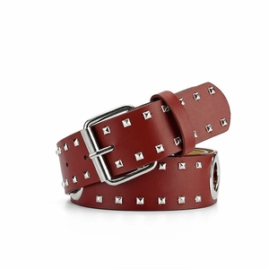 Detail van donkerrode leren riem met zilveren gesp en drie rijen vierkante metalen studs