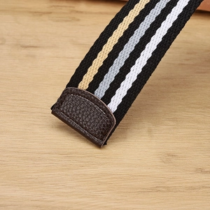 Close-up of a striped braided elastic belt featuring litchi grain leather tip detailing
