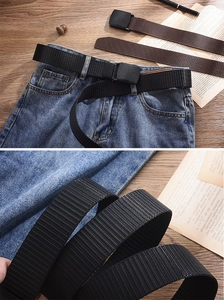 Detail of durable nylon tactical canvas belt with matte black buckle on denim jeans