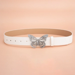 Détail d'une ceinture en cuir blanc dotée d'une boucle papillon ornée de strass brillants