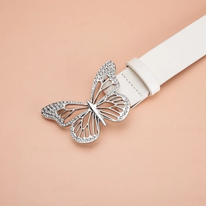 Vue détaillée de la boucle papillon argentée avec strass sur une ceinture blanche