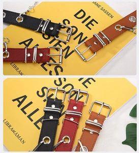 Close-up of punk style PU leather belts with silver metal eyelets and decorative chains