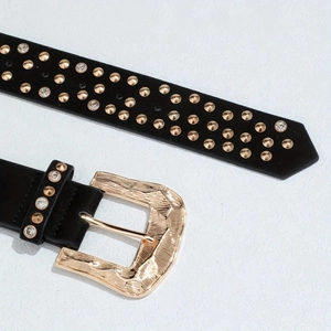 Detail de ceinture en daim noir avec clous dores et boucle metallique texturee