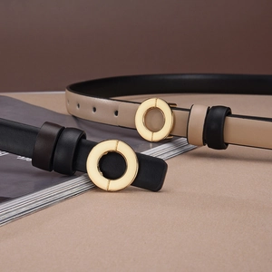 Detail of slim black and apricot leather belts with elegant golden round metal buckles