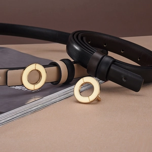 Detail of slim black and beige leather belts with minimalist round gold buckles