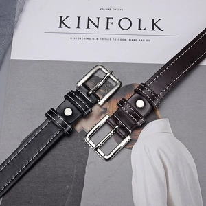 Detail of black and brown leather eyelet belts with contrast stitching and metal buckle