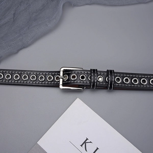 Detail of black leather belt featuring full metal eyelets and white contrast stitching