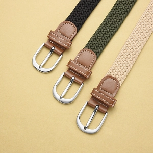 Close-up of three elastic braided belts in black, green, and beige with metal buckles