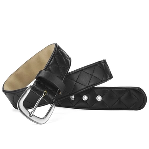 Détail de la texture en cuir noir matelassé et boucle argentée sur une ceinture large