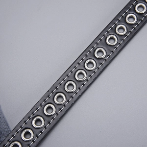 Detail of black leather belt with white stitching and silver metal eyelets