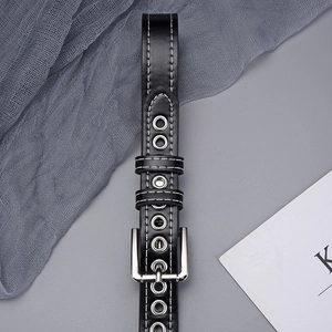 Detail of black grommet belt featuring silver square buckle and white contrast stitching