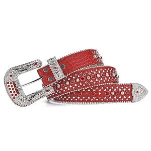 Dettaglio della cintura rossa coccodrillo con borchie argentate, stelle e strass rossi
