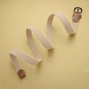 Detail of beige woven elastic belt with brown faux leather trim and metallic buckle