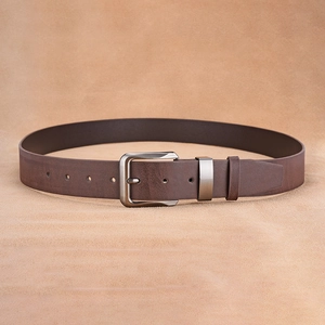 Detail of vintage brown leather belt with brushed metal buckle and adjustment holes