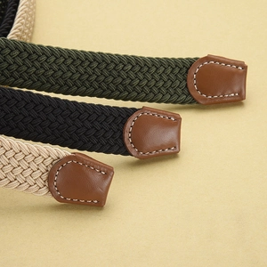 Detail of woven elastic belts in green, black and beige with brown leather tips