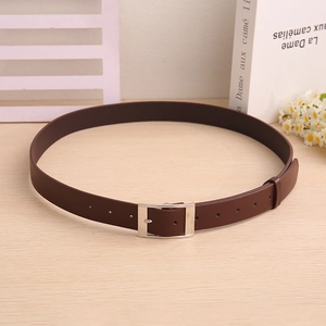 Detailed view of deep brown faux leather belt with a silver square buckle on wood