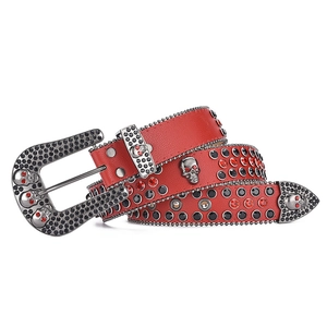 Detailed macro view of red rhinestone belt featuring silver skull studs and metal buckle