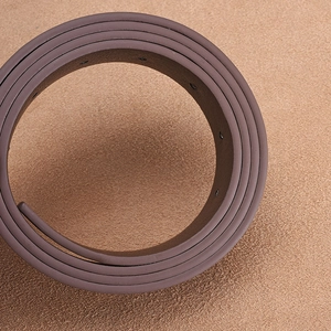 Close-up of a dark brown faux leather belt featuring fine matte texture and neat holes