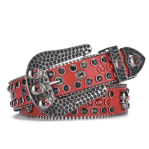 Macro detail of red punk belt with rhinestone skull buckle and dark gothic metal hardware