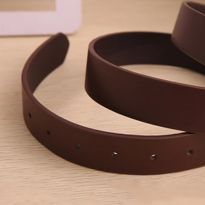 Macro shot of brown matte leather belt with rounded adjustment holes on wood background