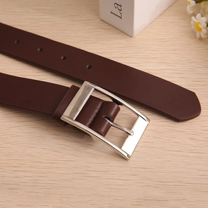 Detailed close-up of brown leather belt with silver metal pin buckle on wooden surface
