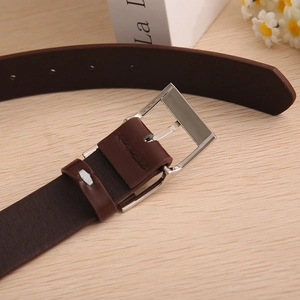 Detail shot of men's dark brown leather belt with silver metal pin buckle on wood background
