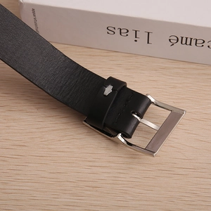 Macro detail of black lychee grain leather belt with a silver square metal pin buckle