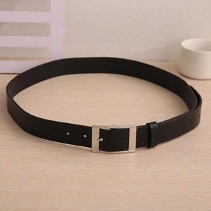 Close-up of a men's black leather belt with silver metal pin buckle on a wooden desk
