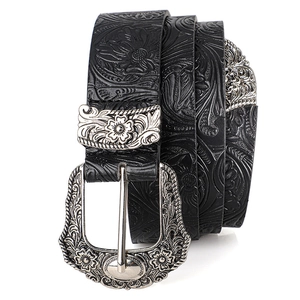 Detail of vintage Western leather belt with embossed floral patterns and silver buckle