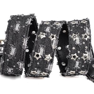 Detailed view of black denim punk belt with star rivets and distressed frayed edges