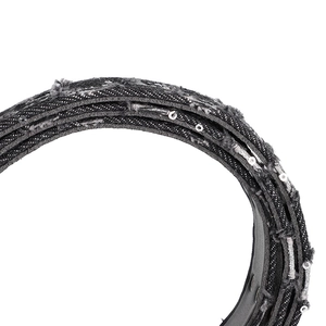 Detailed close-up of punk black denim fabric with frayed edges and silver sequins