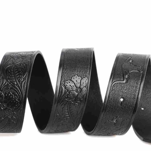 Detailed close-up of black leather belt with embossed floral and crocodile patterns