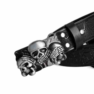 Close-up of vintage punk belt with three silver skulls and floral embossed leather