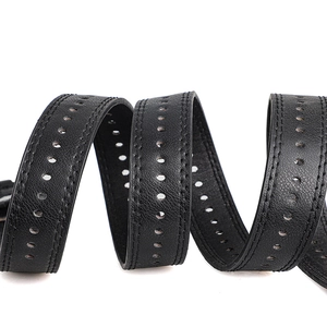 Detail view of black leather belt with circular perforations and double stitching