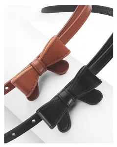 Gros plan de fines ceintures à nœud noires et marron avec boucles en métal sur fond blanc