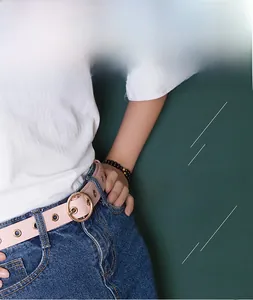 Détail d'une ceinture rose clair en similicuir avec triple rangée d'oeillets dorés