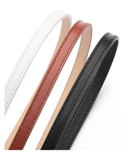 Gros plan de fines ceintures en cuir blanc marron et noir avec coutures précises