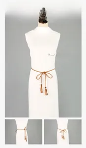 Détail d'une ceinture tressée marron avec glands élégants sur une robe blanche