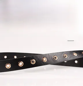 Détail d'une ceinture en similicuir noir avec des oeillets métalliques dorés polis