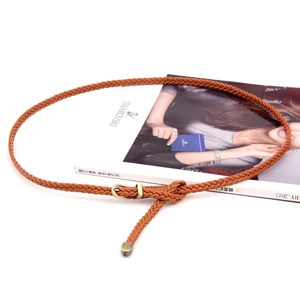 Handwoven brown slim leather belt for women featuring a vintage gold pin buckle on a magazine