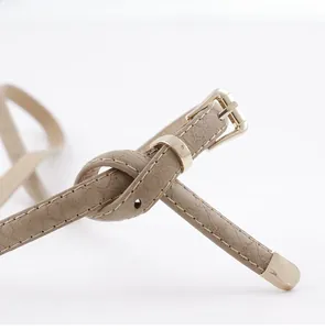 Détail d'une ceinture fine en similicuir kaki avec boucle dorée et texture grainée