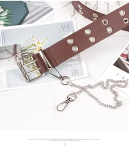 Detail of brown leather punk belt with double silver eyelets and a metal chain accessory