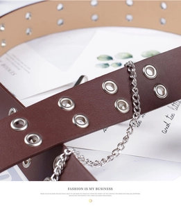 Detail of dark brown leather belt featuring double silver eyelets and a decorative metal chain