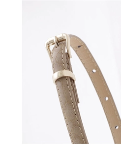 Détail de la ceinture fine en cuir motif serpent kaki avec boucle dorée polie brillante
