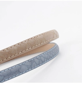 Gros plan sur des ceintures en similicuir crocodile beige et bleu clair avec coutures