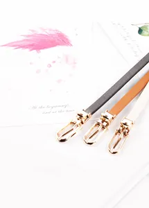 Dettaglio di cinture sottili in pelle nera, marrone e beige con fibbie dorate ovali
