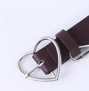 Détail de la boucle métallique argentée en forme de cœur sur une ceinture punk en cuir