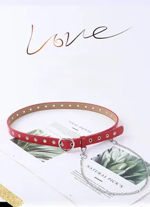 Detail of red faux leather belt featuring heart-shaped silver buckle and metal eyelets