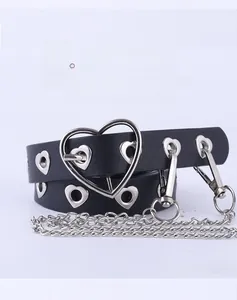 Détail d'une ceinture punk noire avec œillets en cœur, chaînes en métal et boucle en cœur